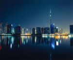 Dubai skyline at night with the Burj Khalifa reflecting in calm waters beneath a clear dark sky