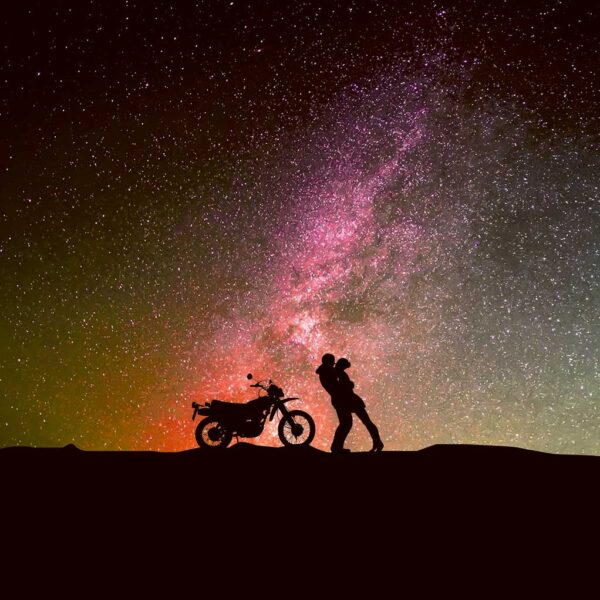 Person standing with motorcycle under a starry sky and the Milky Way galaxy, captured in an LED Box Frame.