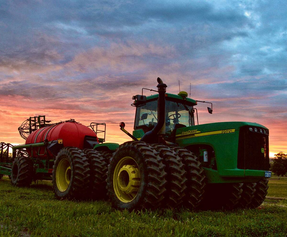 Green John Deere farm tractor in a field, perfect for display in an LED Box Frame for agricultural enthusiasts