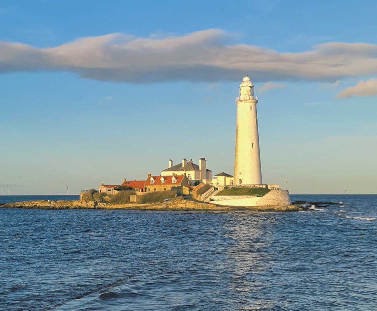 St Mary’s Lighthouse in Newcastle illuminated by golden hour sunlight, standing on a rocky coastal island surrounded by calm sea