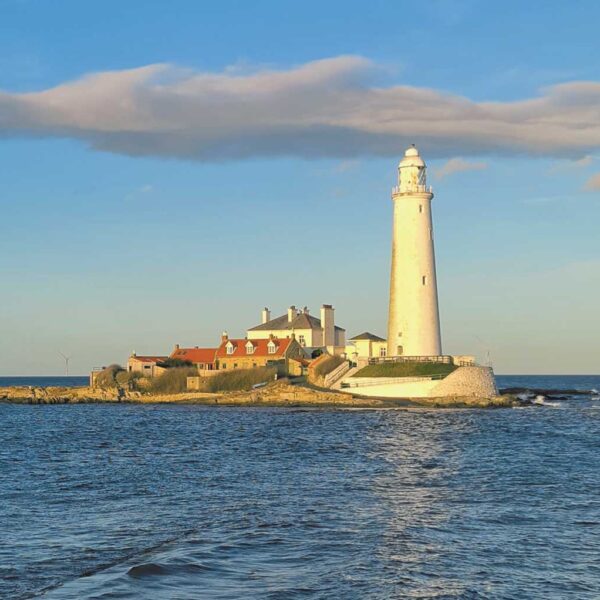 St Mary’s Lighthouse in Newcastle illuminated by golden hour sunlight, standing on a rocky coastal island surrounded by calm sea